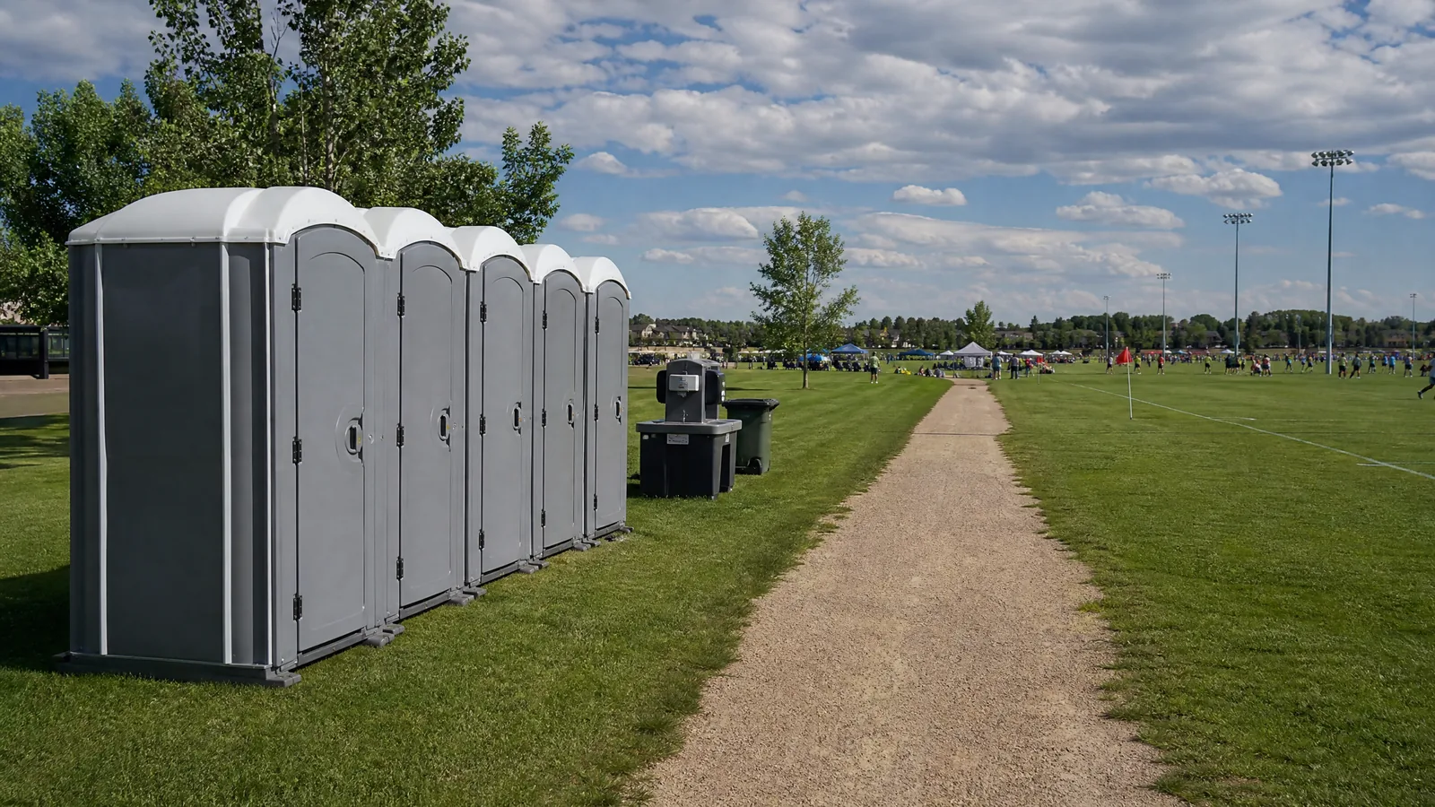Portable restrooms and handwashing support beside a community sports field.